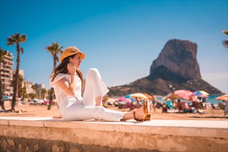 Lifestyle of a young red-haired Caucasian girl dressed in white and with a straw hat on the beaches of Calpe