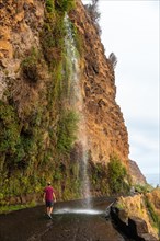 A young man looking at the waterfall that falls on the road called Anjos Waterfall