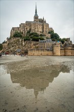 The famous Mont Saint-Michel Abbey reflected in silhouette in the water at low tide on the beach
