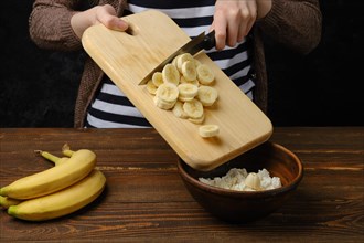 Unrecognizable woman puts sliced banana into a bowl