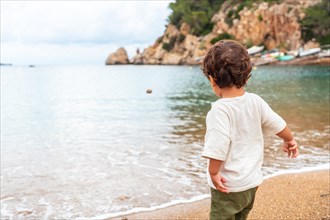 A boy throwing stones on the beach of the port of Sant Miquel