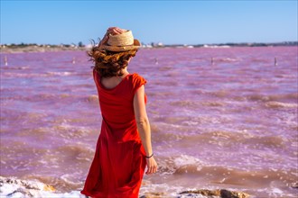 Girl with red dress in the pink lagoon of Torrevieja