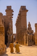 Two local men visiting the Egyptian Temple of Luxor and its precious column