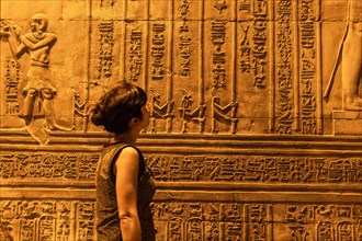 A young woman looking at Egyptian drawings and hieroglyphs at the Temple of Kom Ombo