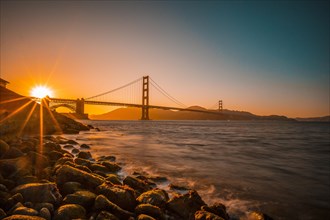 Long exposure Red sunset at the Golden Gate of San Francisco with the sun hiding on the bridge. United States