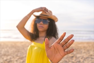 Woman gesturing stop and frame with hand while standing on the beach