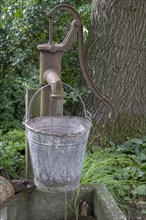 Old Schwengelpumpe and old water bucket made of zinc