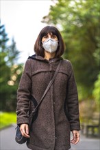 Lifestyle of a Caucasian brunette with short hair and a protective mask for the coronavirus. First walks of the uncontrolled Covid-19 pandemic