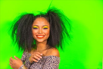 A positive young hipster girl with bright makeup and two tails hairstyle wearing a leopard print dress with open shoulders