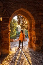 A tourist walking in the sunset at the gate of the Alcazaba wall in the city of Malaga