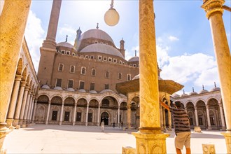 A young tourist looking at the Alabaster Mosque and the gigantic pillars in the city of Cairo