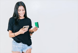 Girl holding credit card shopping online with cell phone isolated. People making online purchases with cell phones and credit cards isolated