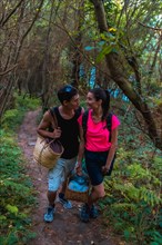 A young Caucasian couple walking and kissing in the mountains on their way to a lovely summer picnic
