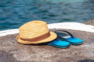 Hat and flip flops next to a natural pool