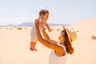 Young mother playing with her son on vacation in the dunes of Corralejo Natural Park
