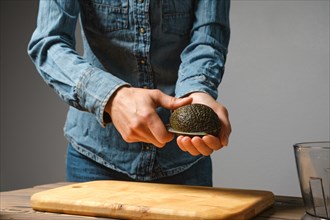 Close up of woman hands cutting fresh avocado with knife in the kitchen