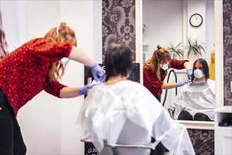 Hairdresser with mask and gloves cutting the ends to the client