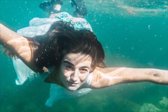 A young woman will dive with a white dress swimming