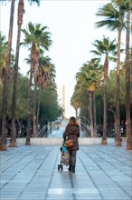 A young woman walking next to the palm trees in the Belen street of the Rambla de Almeria
