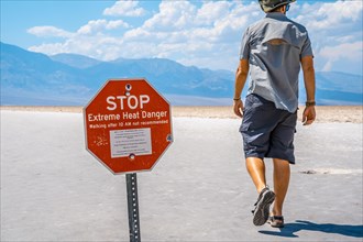 A man tourists walking white salt of Badwater Basin alerted by extreme heat