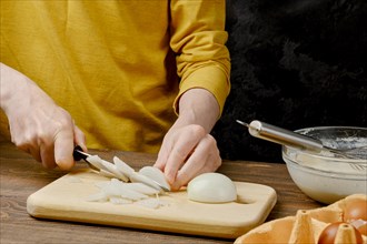 Unrecognizable man slicing white onion for omelet