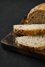 Sliced artisan bread with sunflower seeds on black background