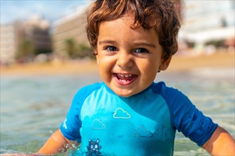 One year old boy bathing in the sea smiling