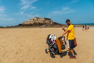 A young father enjoying the summer on the Grande Plage du Sillon de Saint-Malo in French Brittany