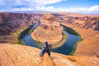 Crossed feet resting watching Horseshoe Bend and the Colorado River in the background