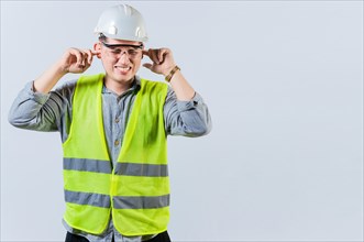 Young engineer covering ears isolated. Engineer man with ear pain. Concept of engineer covering his ears with pain expression