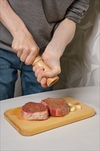 Sprinkling steak with salt from hand grinder