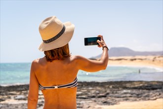 A young tourist taking a photo on the beaches of the dunes of the Corralejo Natural Park