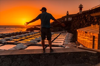 A young man enjoying the sunset of the Fuencaliente Lighthouse next to the salt mine