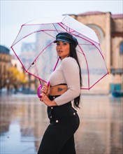 Street Style of a young brunette Latina in the rain of the city with an umbrella