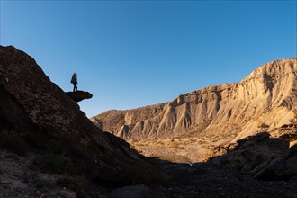 Silhouette of a young woman climbing on a stone in the Tabernas desert