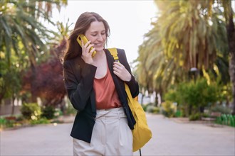 Casual woman with a yellow bag talking to the mobile phone outdoors