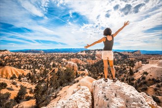 A girl with her arms outstretched enjoying the views from the Sunrise Point in Bryce National Park. Utah