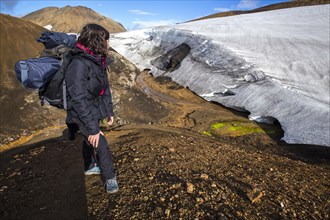 A young woman looking at a glacier at the highest point of the 4-day trek from Landmannalaugar. Iceland