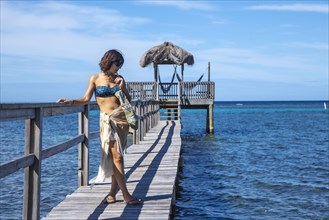 A young girl on a wooden walkway above the Caribbean Sea on Roatan Island. Honduras