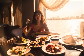 A young tourist having dinner on a boat on the nile a traditional Egyptian meal with sunset light in the window