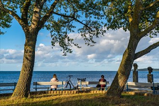 People sitting on the bench at the Utkiek lookout point with a view over the Greifswald Bodden