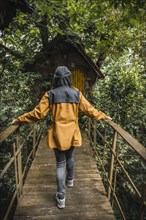 A young woman in a yellow jacket visiting a haunted house in a forest. Mystical photography