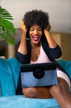 Young entrepreneur of black race and afro hair making a video call with great joy and amazement