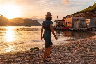 A young woman walking along Benirras beach in Ibiza