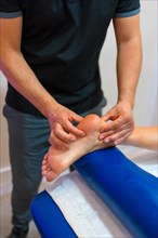 Physiotherapeutic massage to an unrecognizable woman lying on a stretcher on the foot