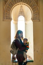 A young woman with her son visiting the courtyard with water fountains inside the Alcazaba in the city of Malaga