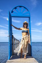 A young girl at a blue door in the Caribbean Sea on Roatan Island. Honduras
