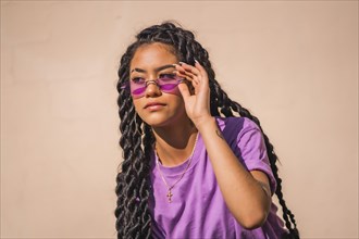 A young dark-skinned woman with purple glasses in an urban session of Latin ethnicity