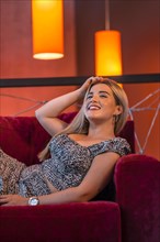 Portrait of a young blonde woman lying on the sofa in a nightclub
