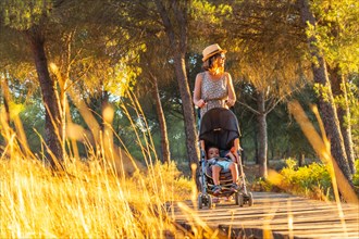 A young woman walking with her son along the wooden walkway in the Donana natural park at sunset. Huelva